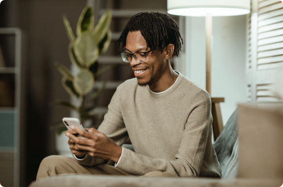 Homem negro mexendo no celular e sorrindo